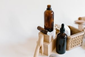 bottles of peppermint oil with other care items on white background for preventing head lice